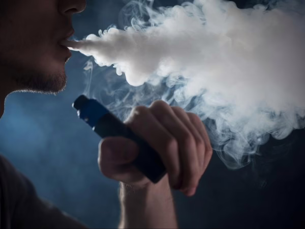 Orang memegang botol liquid vape lokal dengan label khas, dikelilingi uap tebal, menonjolkan kekuatan brand dan storytelling-nya.